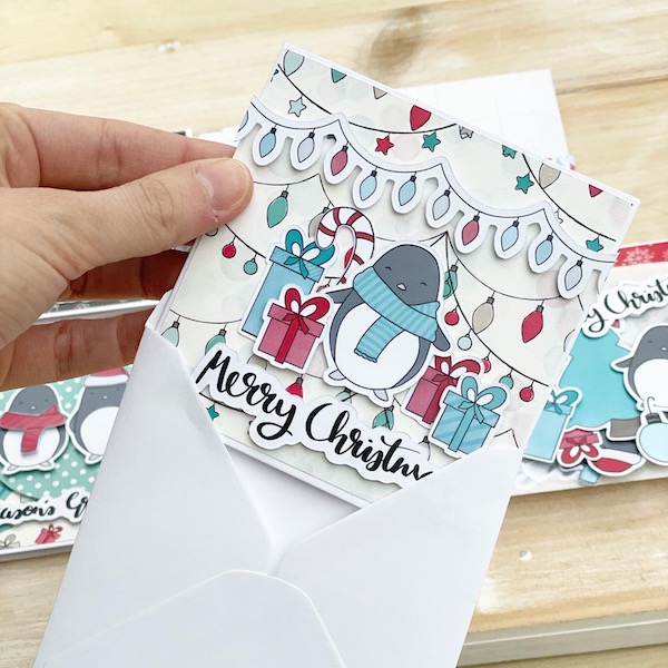Cute handmade penguin christmas card being put in an envelope